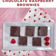 Five Chocolate Raspberry brownies & fresh raspberries atop a white plate on a white towel with red hearts on a pink scarf Pinterest banner.