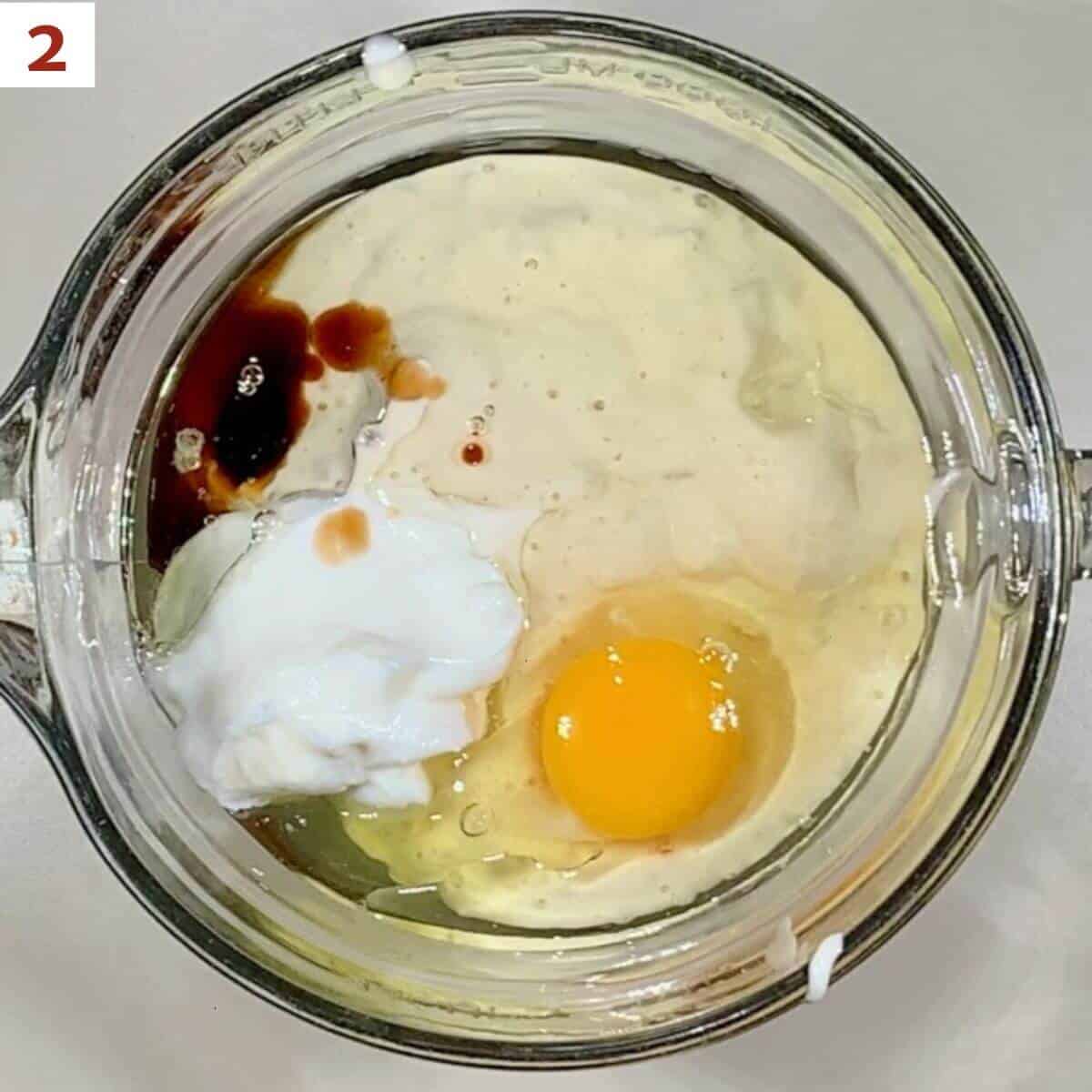 Mixing the sourdough starter, egg, canola oil, sour cream, and vanilla in a glass bowl from overhead.