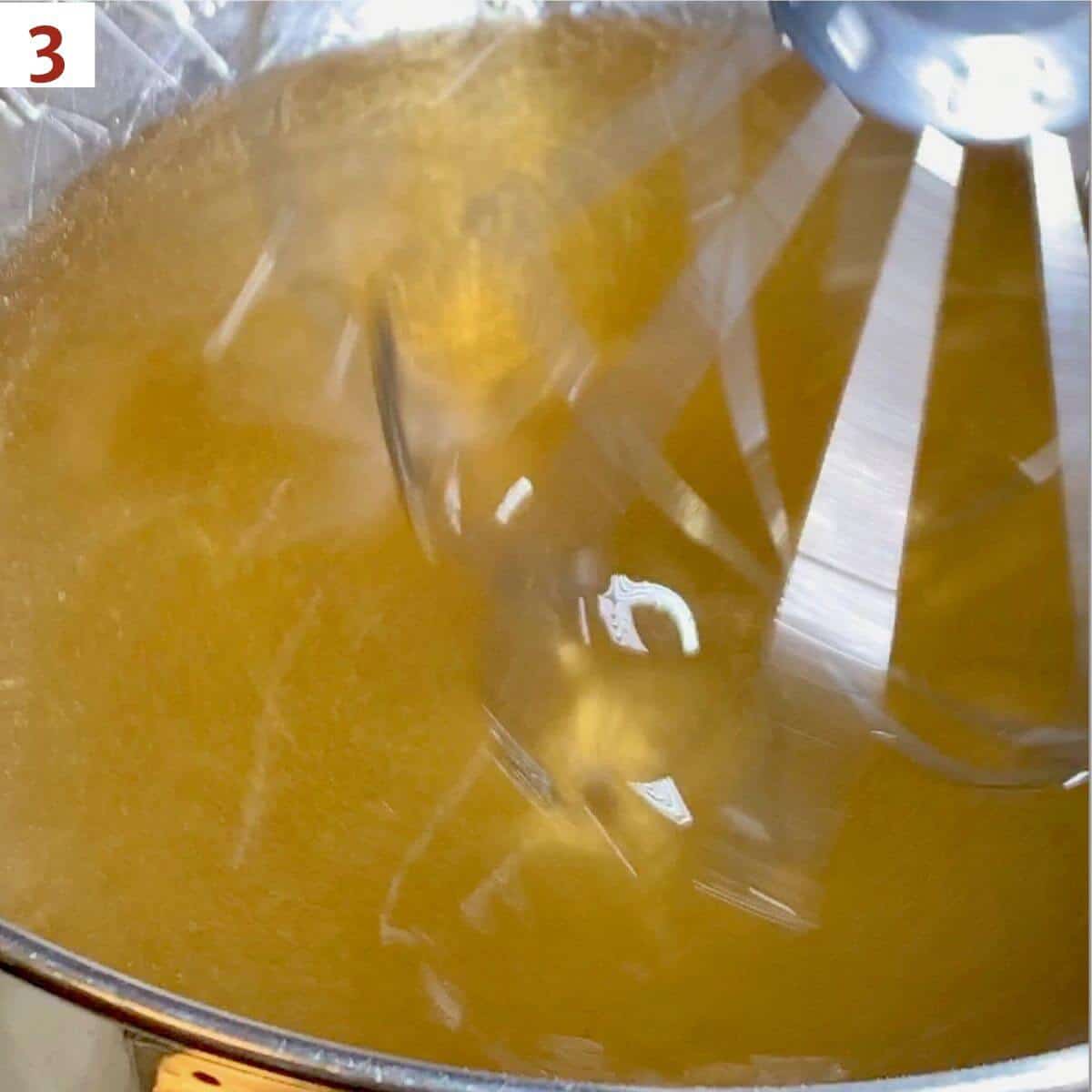 Pouring simple syrup into gelatin mixture as it's being whipped.