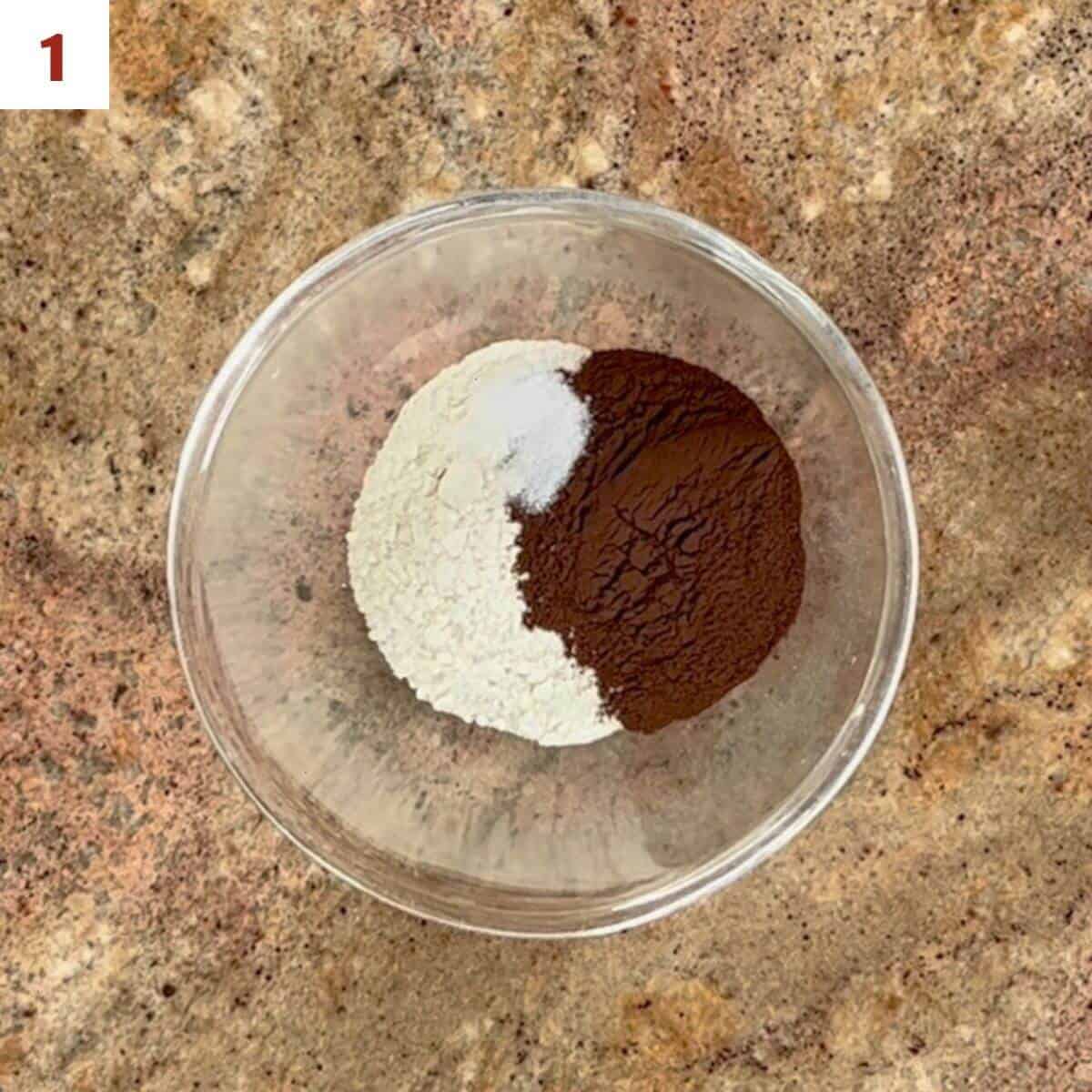 Flour, dark chocolate cocoa powder, and salt in a glass mixing bowl from overhead.