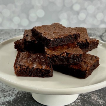 Stack of bourbon brownies on a white cake stand.