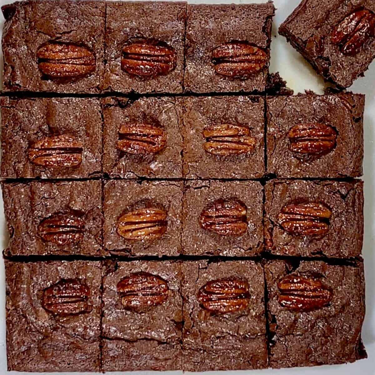 Cut whiskey brownies topped with candied pecans with the upper corner turned diagonally.