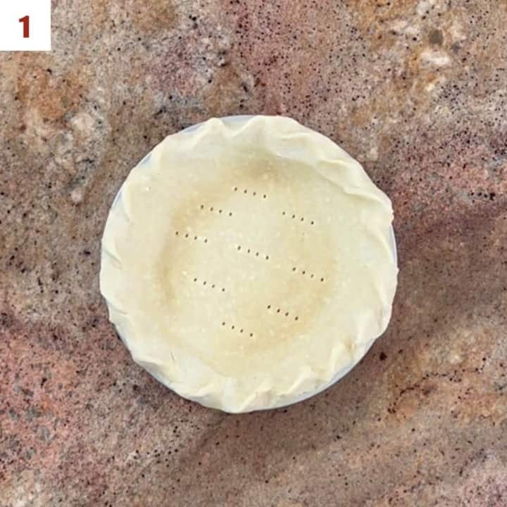 Unbaked pie crust pricked with a fork in a pie pan from overhead.