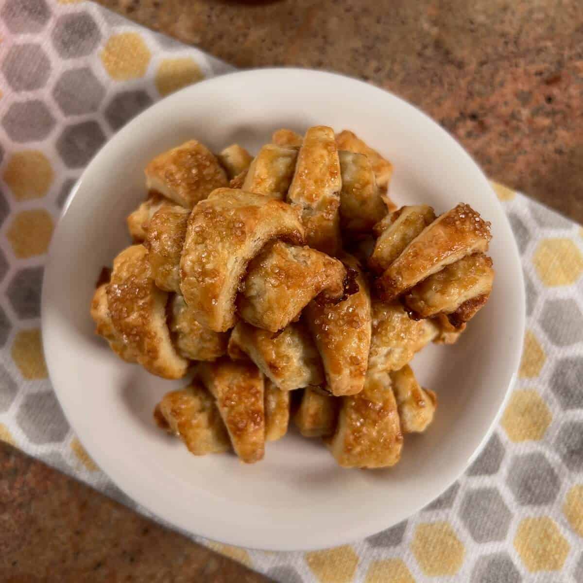 Apple Cinnamon Rugelach stacked on a white plate from overhead.