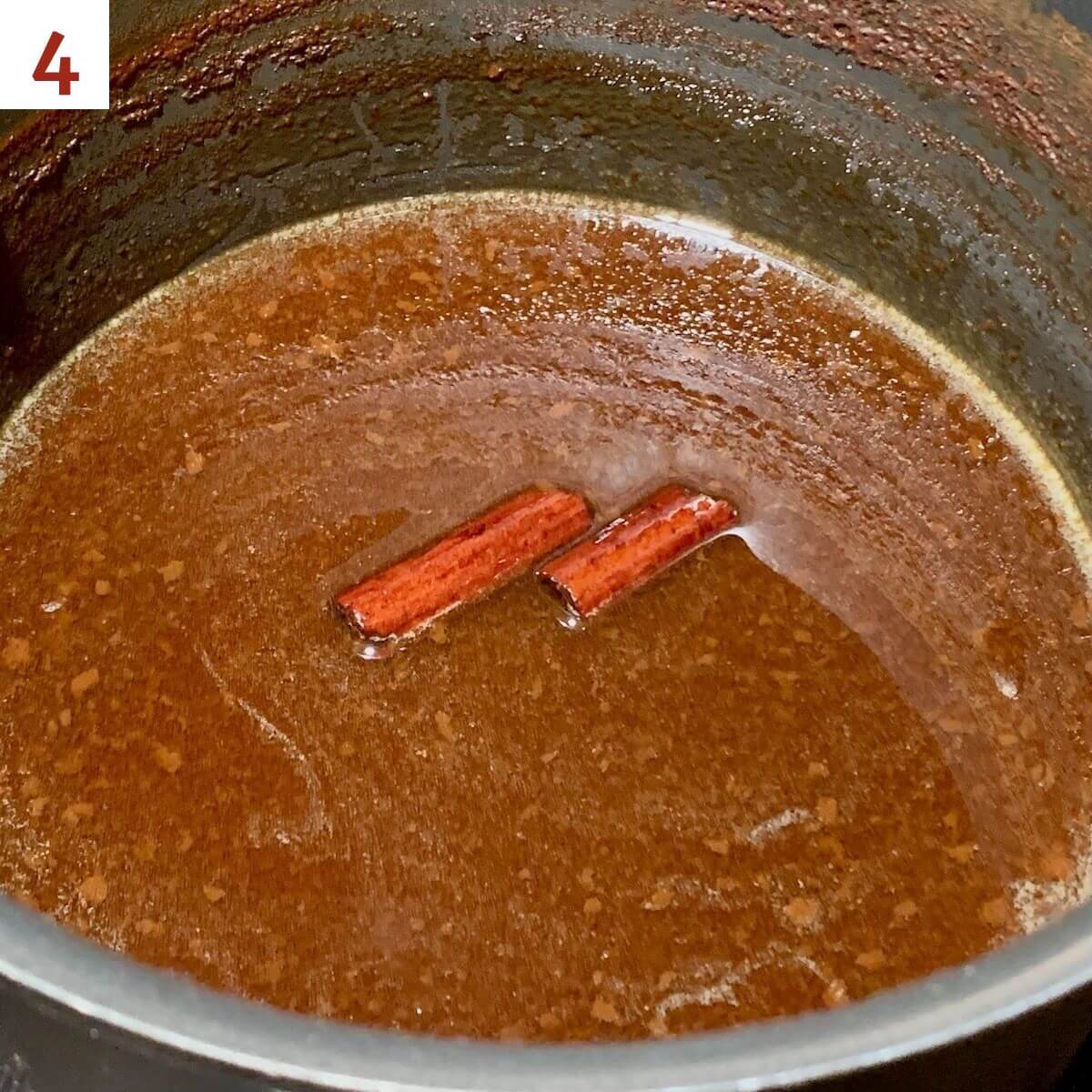 Finished boiled apple cider in the pot with cinnamon sticks
