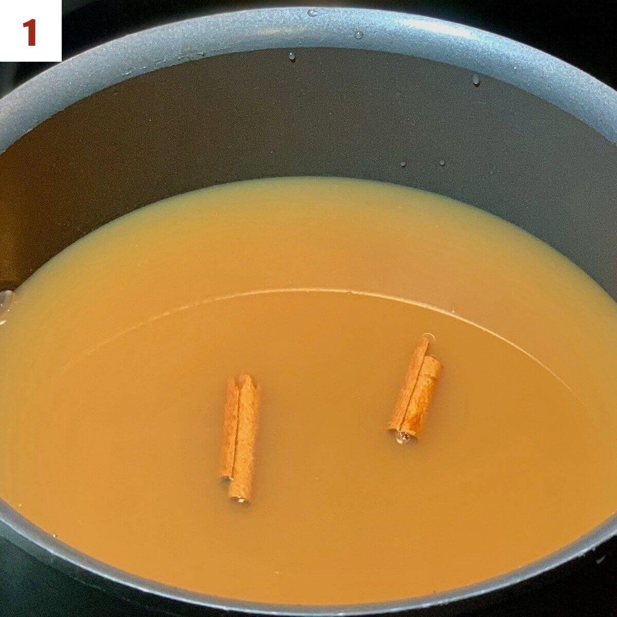 Apple cider in the pot with cinnamon sticks.