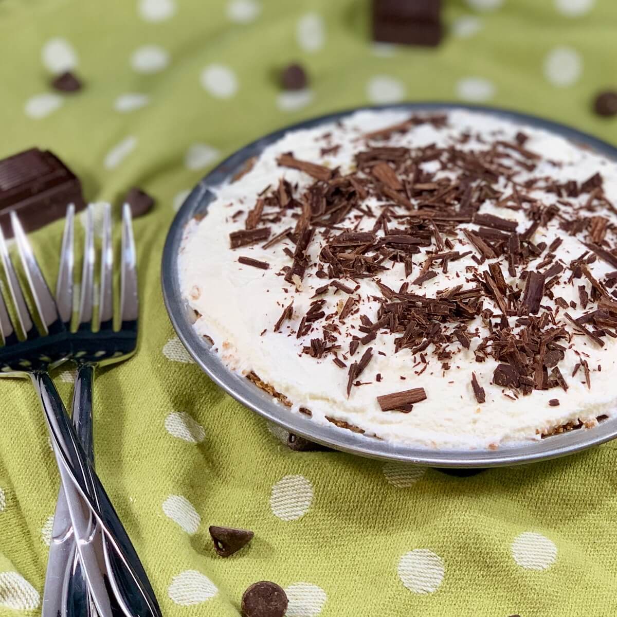 Chocolate Cream Pie with 2 forks surrounded by chocolate on a green polka dot towel.