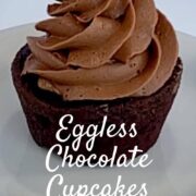 One eggless chocolate cake frosted with chocolate buttercream on a white plate Pinterest banner.