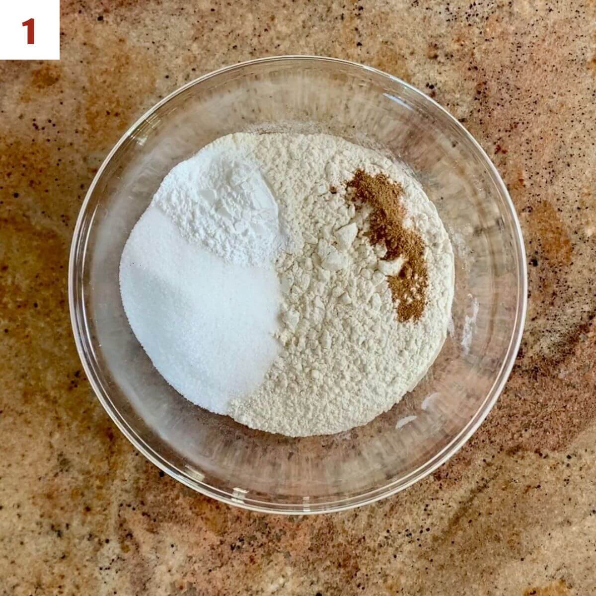 Flour, sugar, baking powder, nutmeg, & salt in a glass bowl.