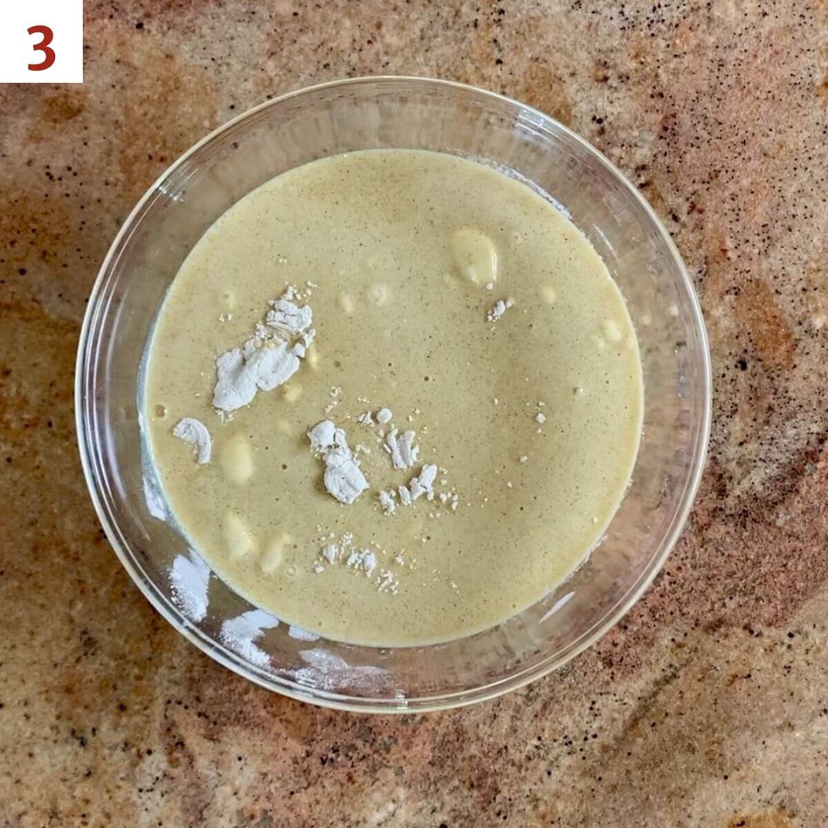 Eggnog mixture poured atop the flour mixture in a glass bowl.