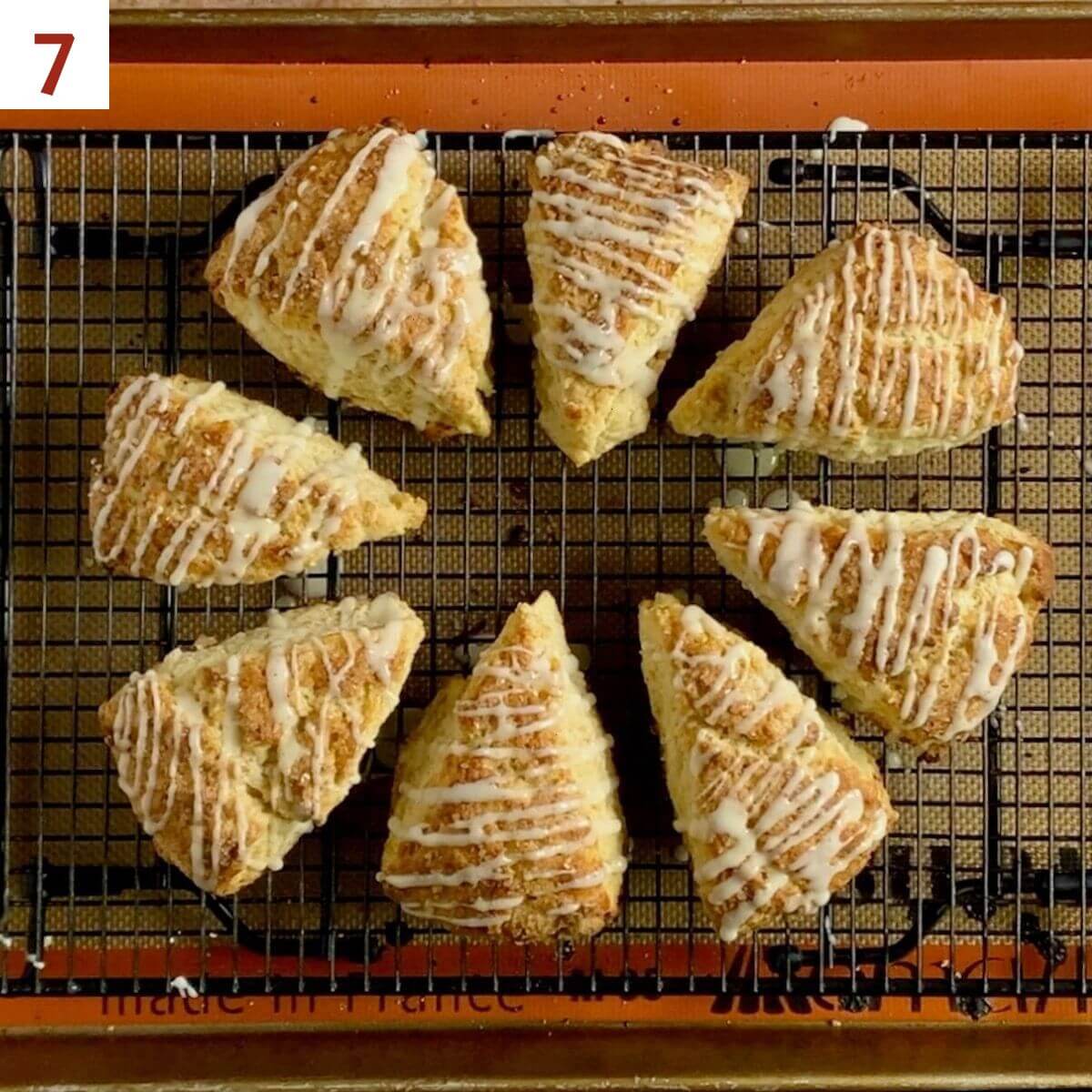 Eight baked and glazed scones on a cooling rack.