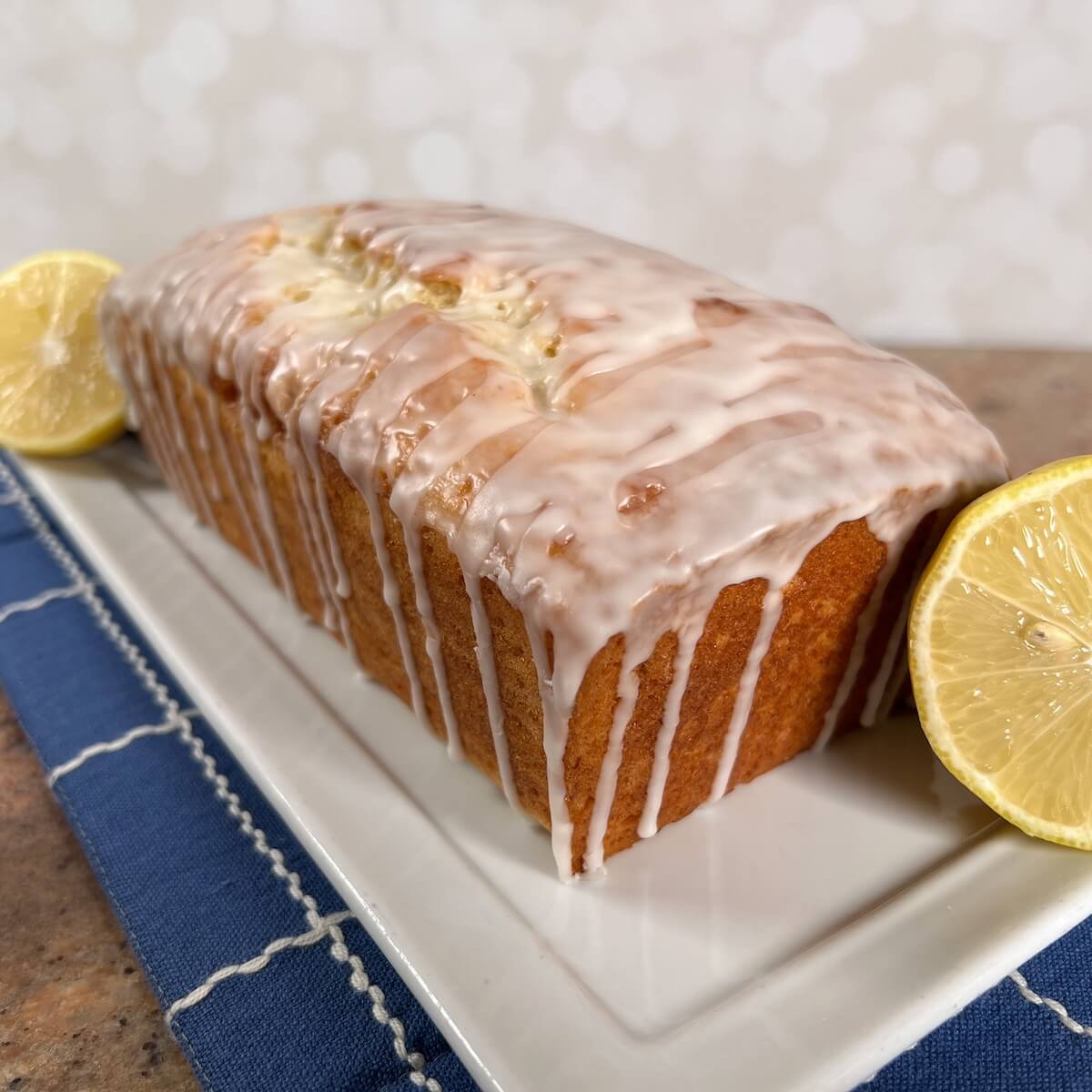 Glazed Limoncello Cake on a white plate with lemons.