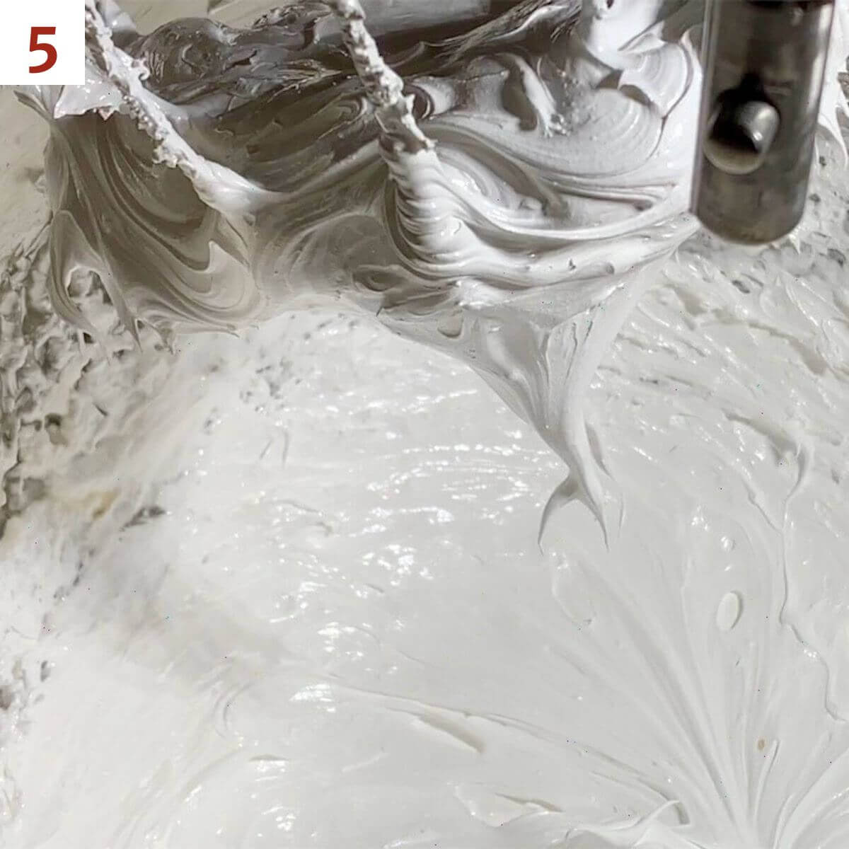 Pulling the whisk full of marshmallow creme out of a mixing bowl.