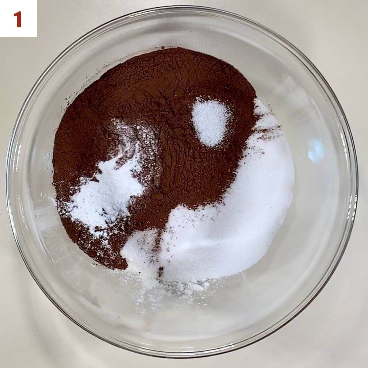 Flour, sugar, cocoa powder, baking soda, baking power, & salt in a glass bowl.