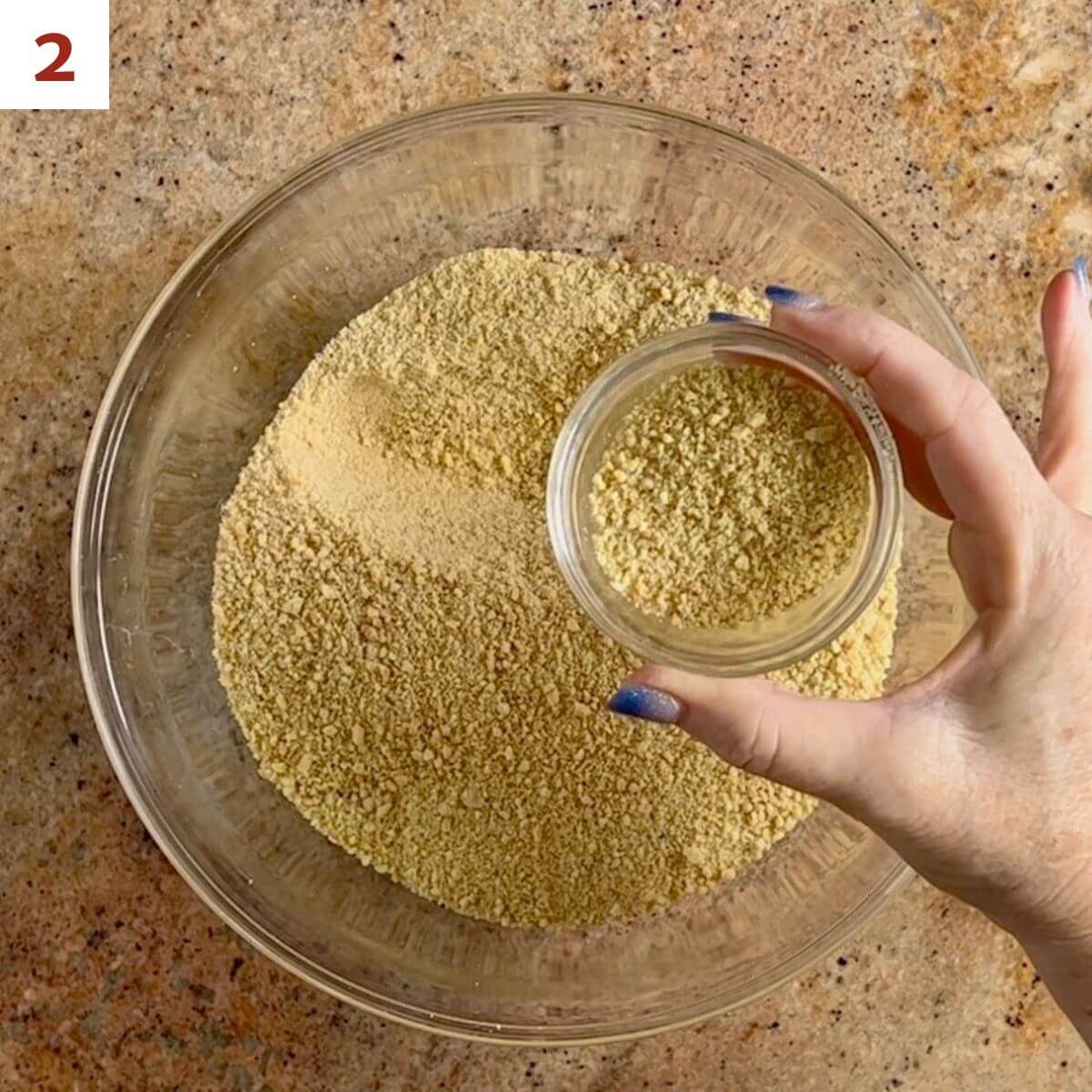 Reserving ladyfinger crumbs in a glass dish.