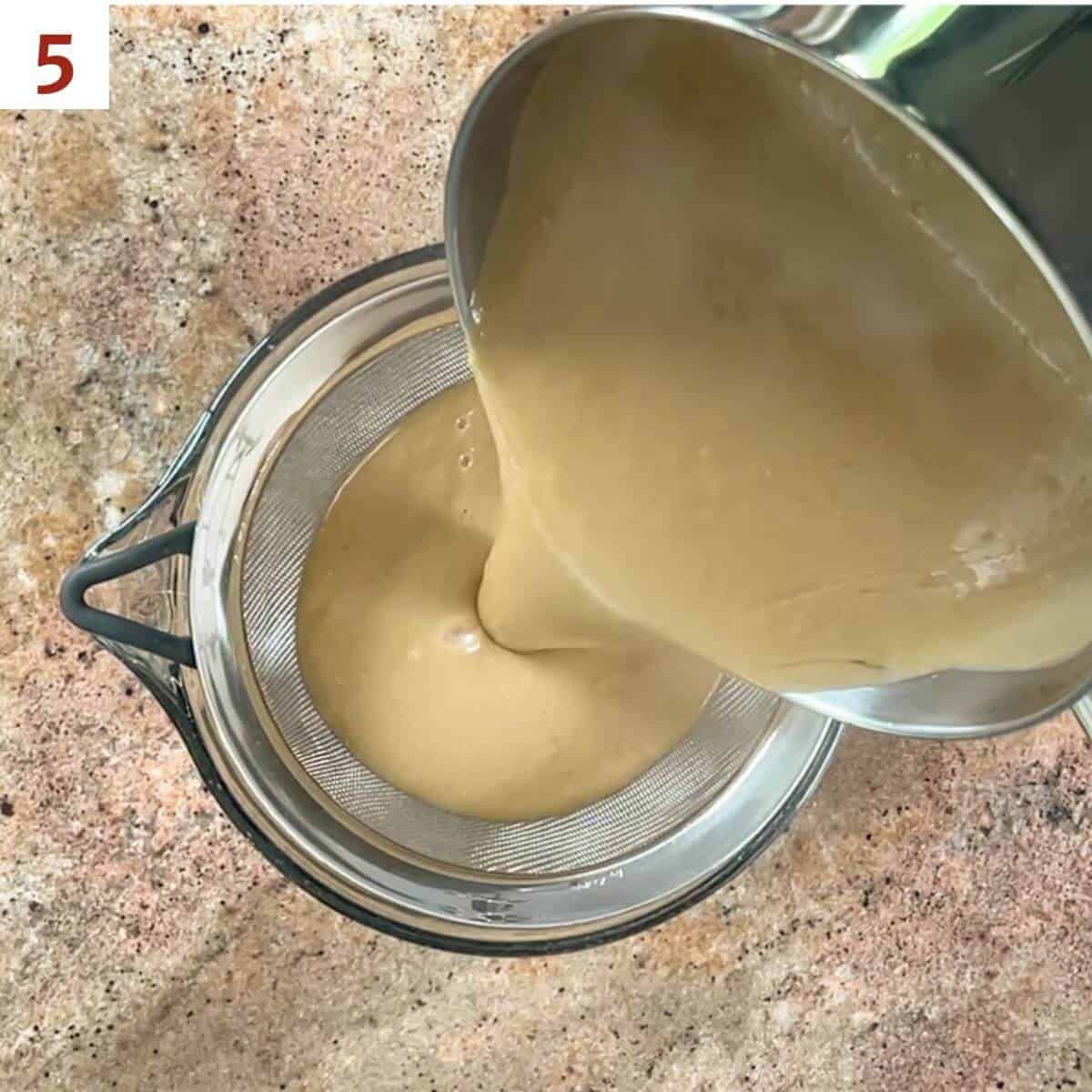 Straining the hot pudding through a fine mesh sieve.