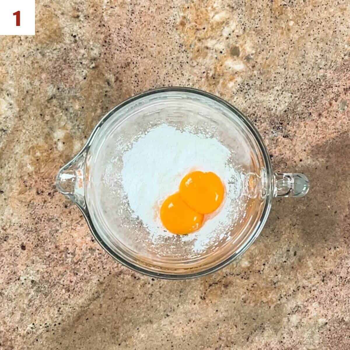 Egg yolks and cornstarch in a glass bowl from overhead.
