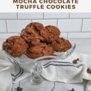 Mocha Chocolate Truffle Cookies stacked on a glass cake stand surrounded by a white towel with a blue stripe & chocolate chips Pinterest banner.