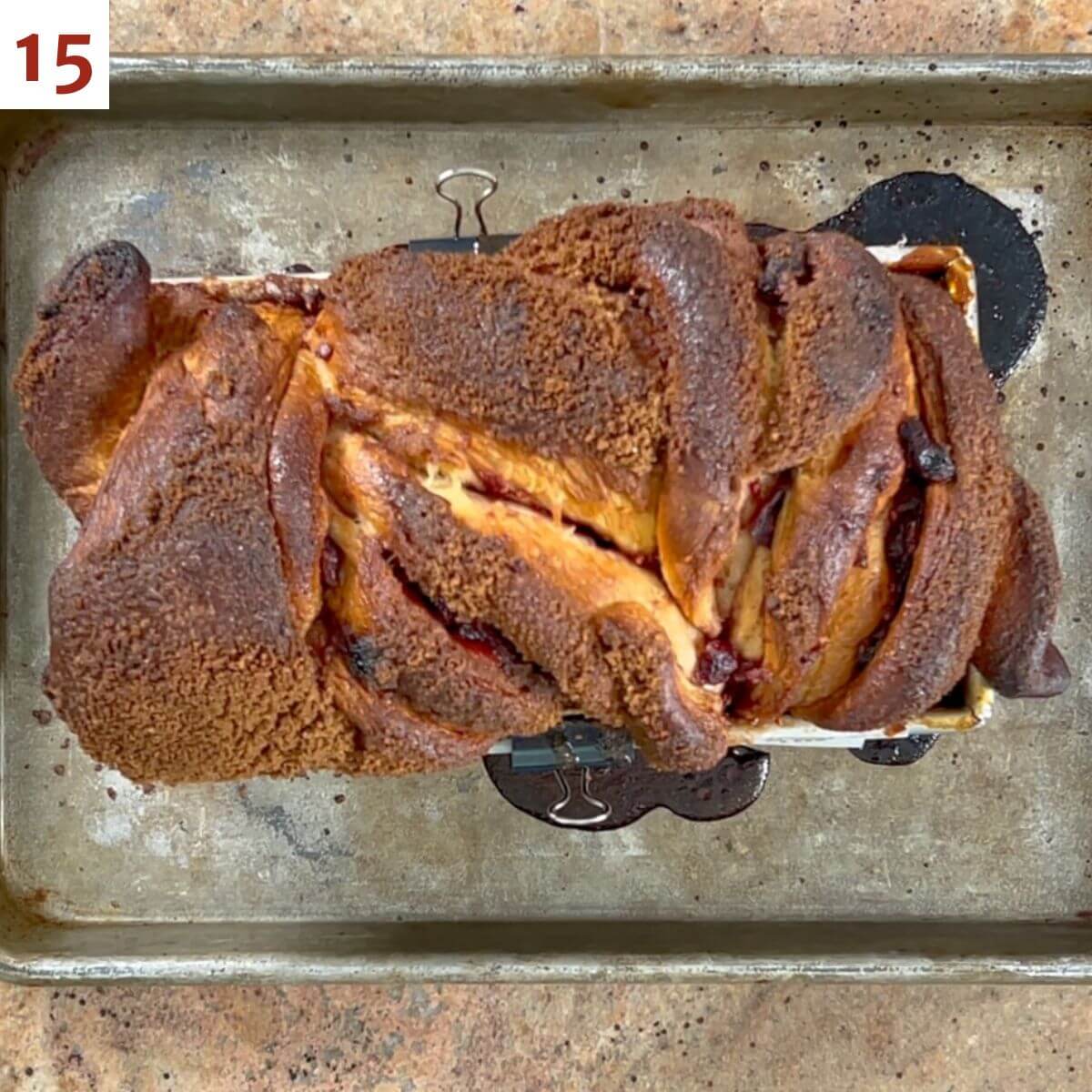 Baked cinnamon cranberry swirl bread in the pan on a quarter sheet baking pan.