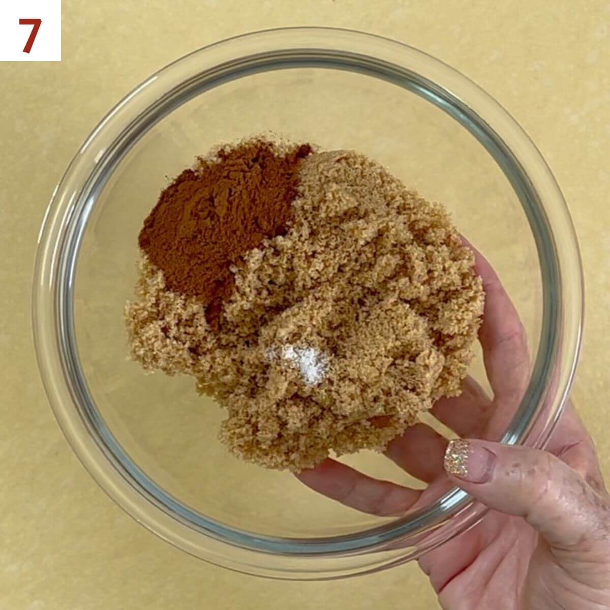 Mixing brown sugar, cinnamon, and salt in a glass bowl.
