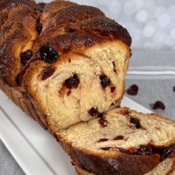 Sliced cranberry cinnamon swirl bread on a white plate viewed from the side.