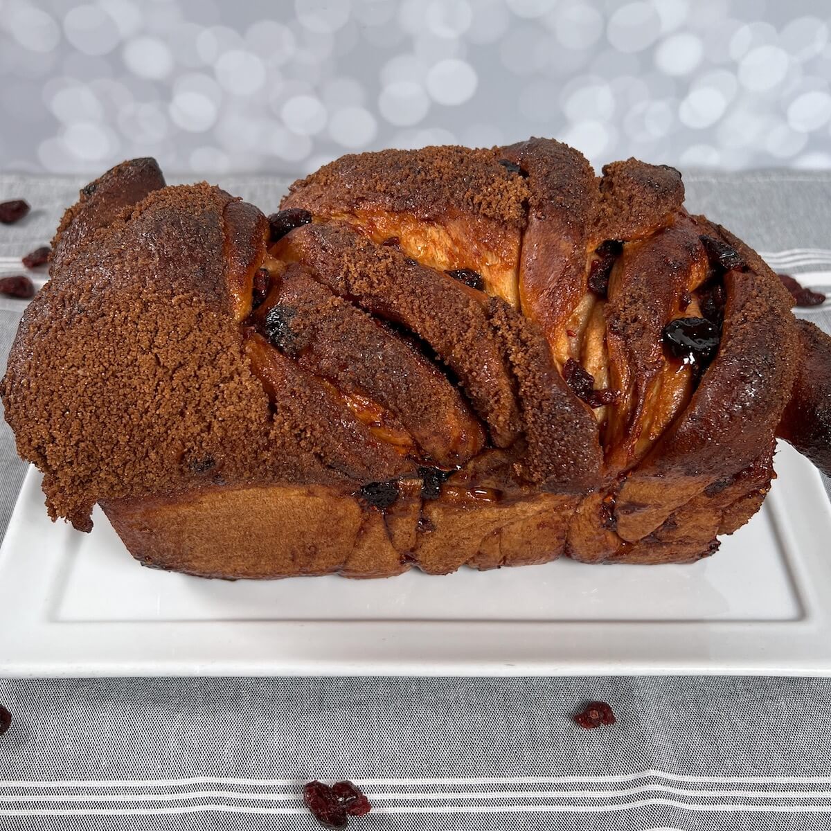 Whole cranberry cinnamon swirl bread on a white plate.