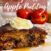 Slice of sticky toffee apple pudding on a plate with the rest of the cake on a cake stand with jug of honey toffee sauce and apples behind Pinterest banner.