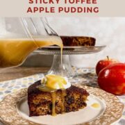 Pouring honey toffee sauce onto a slice of sticky toffee apple pudding on a plate with the rest of the cake on a cake stand and apples behind Pinterest banner.