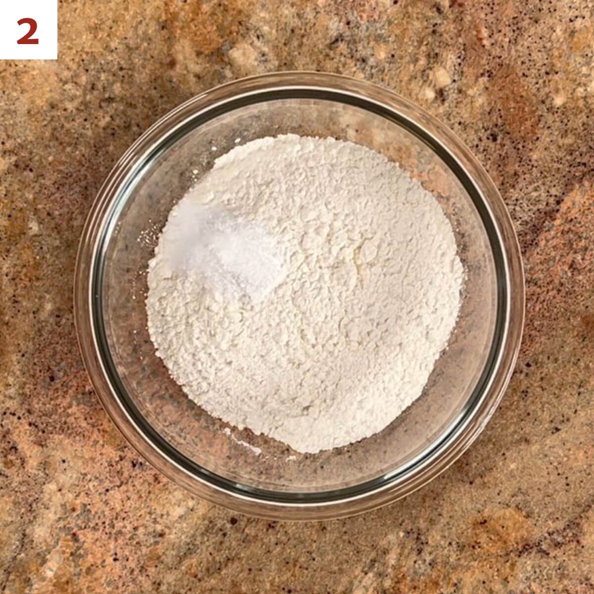 Flour, baking powder, baking soda, and salt in a glass bowl.