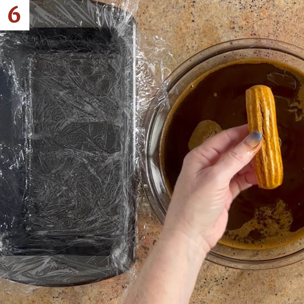 Dipping a ladyfinger quickly into the espresso mixture before laying in the loaf pan.