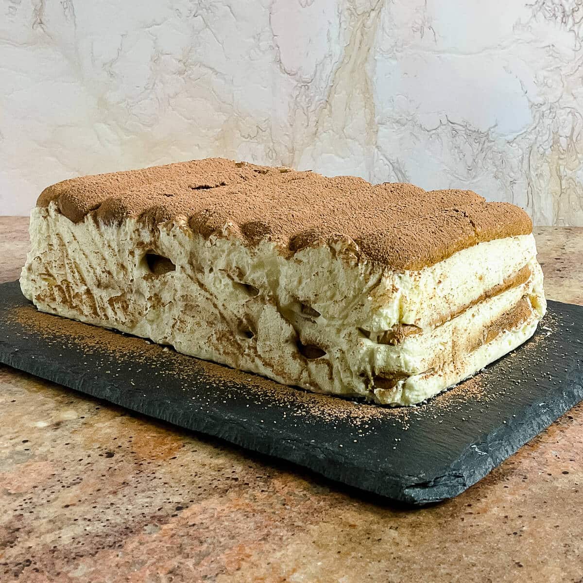 Whole Tiramisu loaf on a black platter.