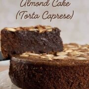 Flourless Chocolate Almond Cake on a cake stand with a slice lifted up Pinterest banner.