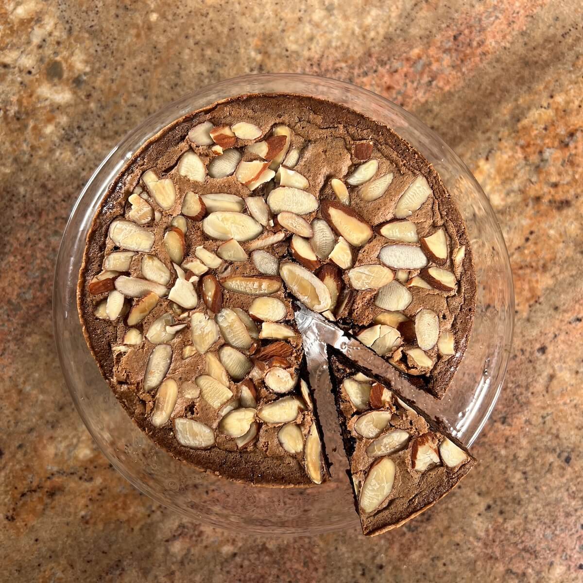 Flourless Chocolate Almond Cake on a cake stand with a slice moved out.