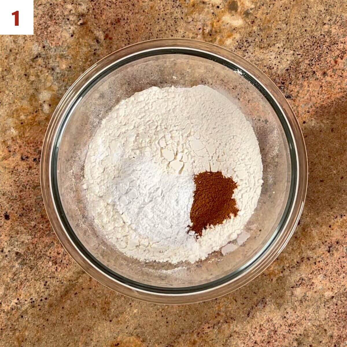 Flour, baking powder, cinnamon, and salt in a glass bowl.