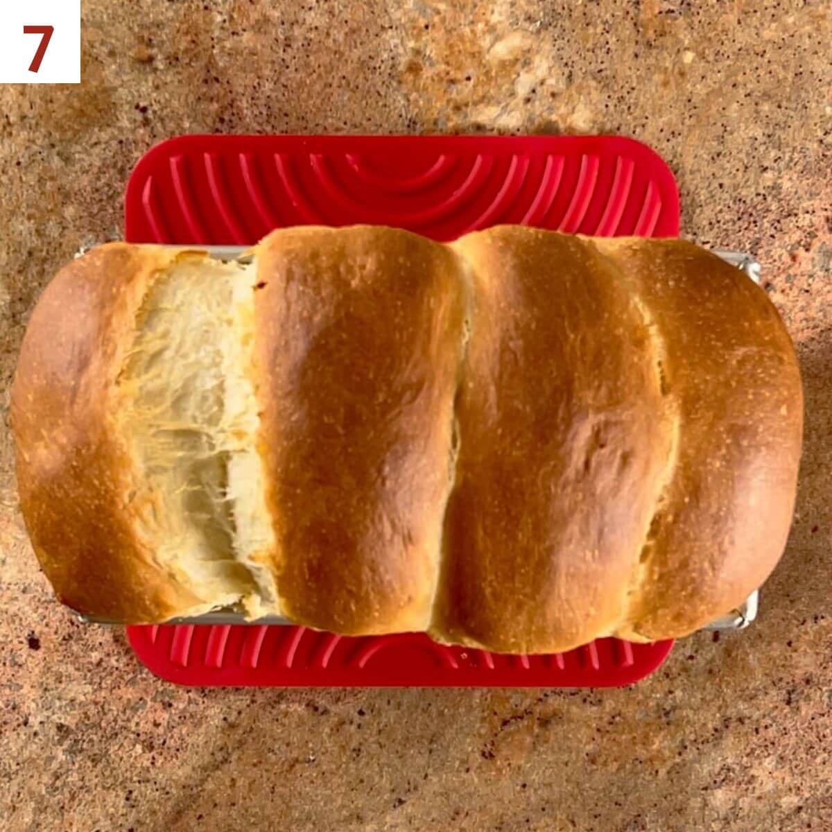 Freshly baked sandwich bread on a red trivet.