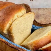 Sliced sourdough discard sandwich bread on a blue towel set in a wooden bowl Pinterest banner.