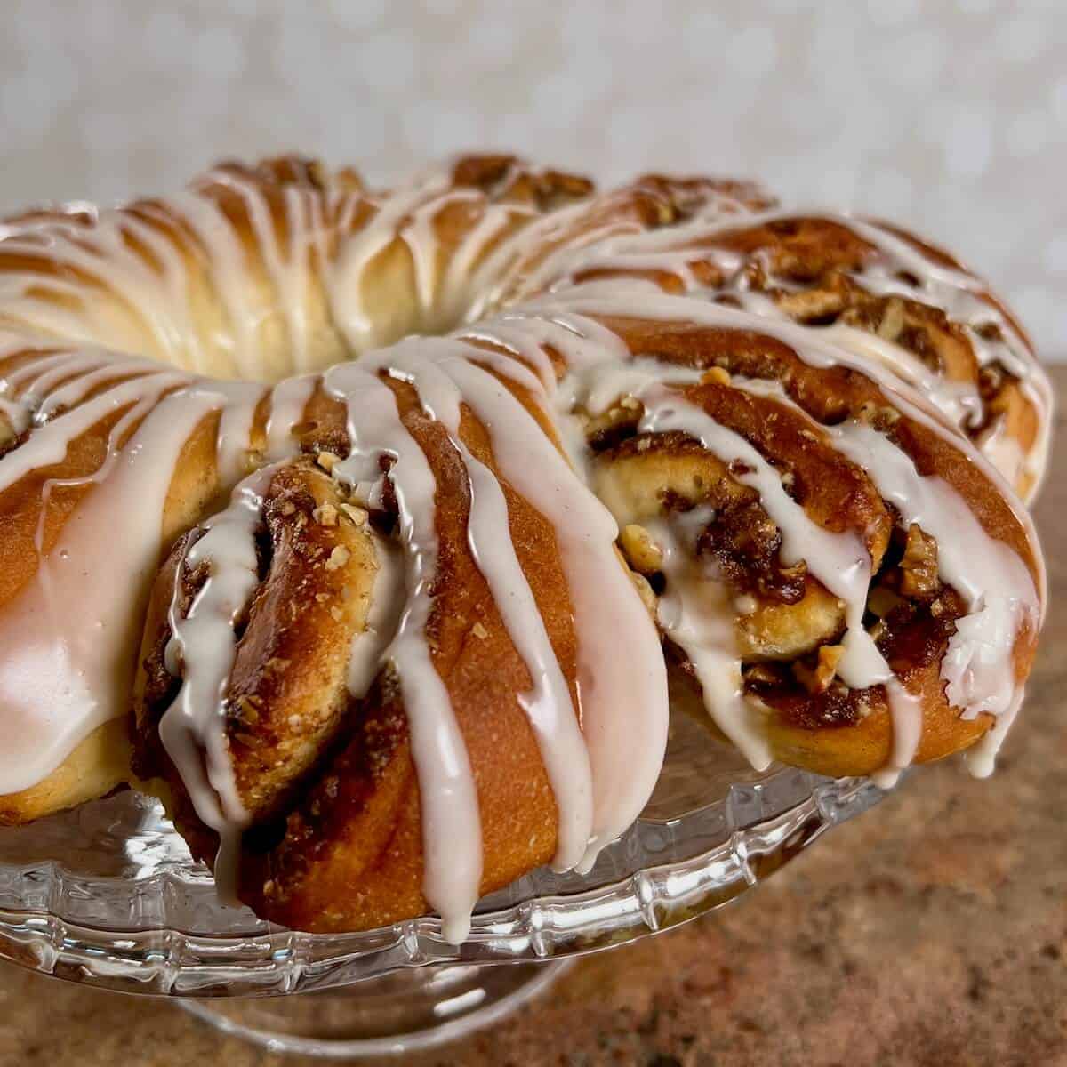 Whole Swedish Tea Ring on a glass cake stand showing spiral detail.
