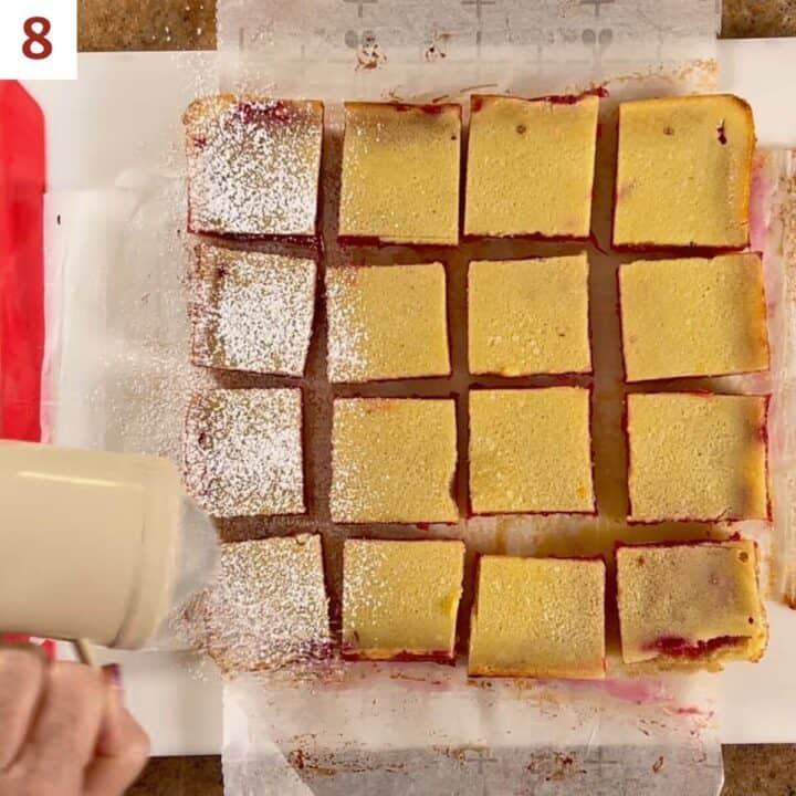 Shaking powdered sugar onto the cut bars.