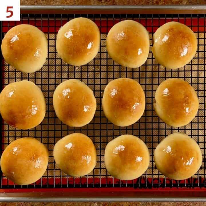 Glazed cream buns on a cooling rack.