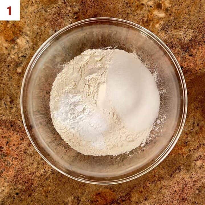 Flour, baking powder, baking soda, and salt in a glass bowl.