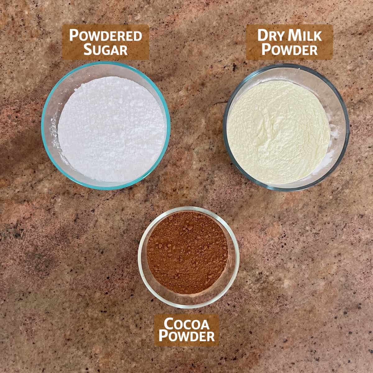 Ingredients for hot cocoa mix portioned into glass bowls.
