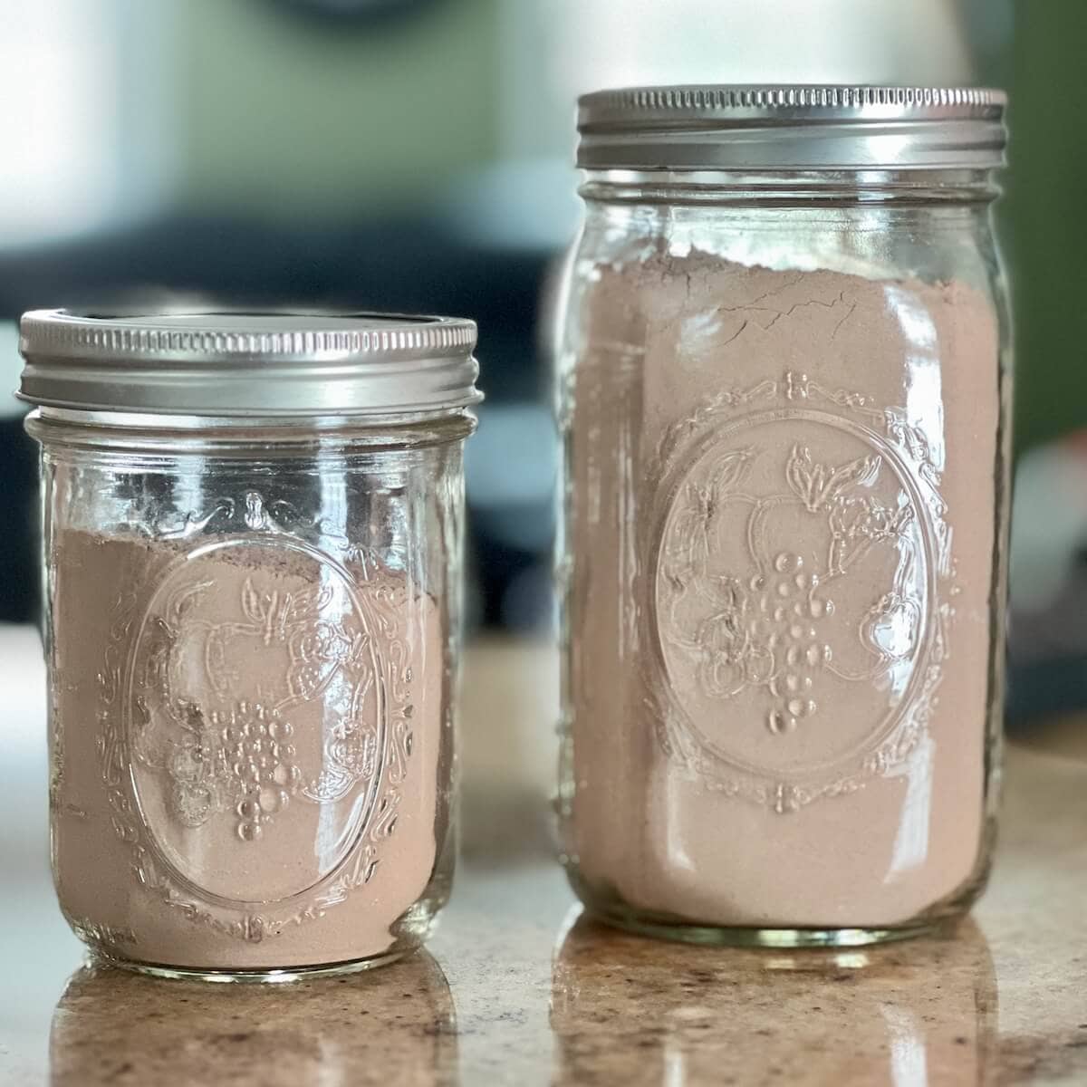Two containers of hot cocoa mix in a pint and quart canning jar.