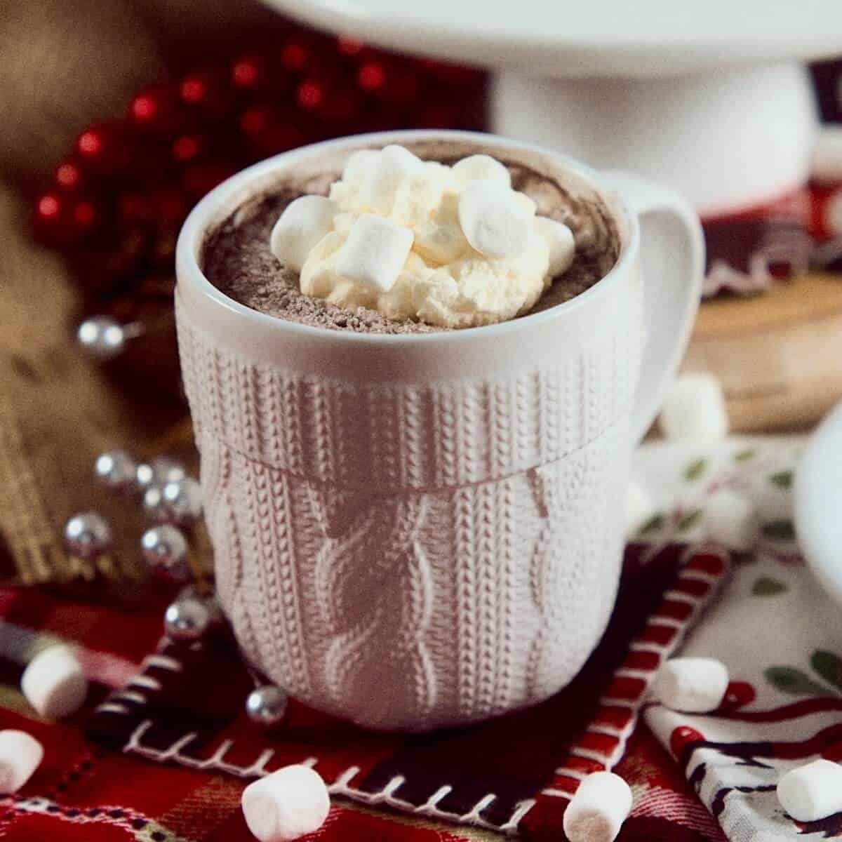 White mug of hot cocoa topped with whipped cream and marshmallows