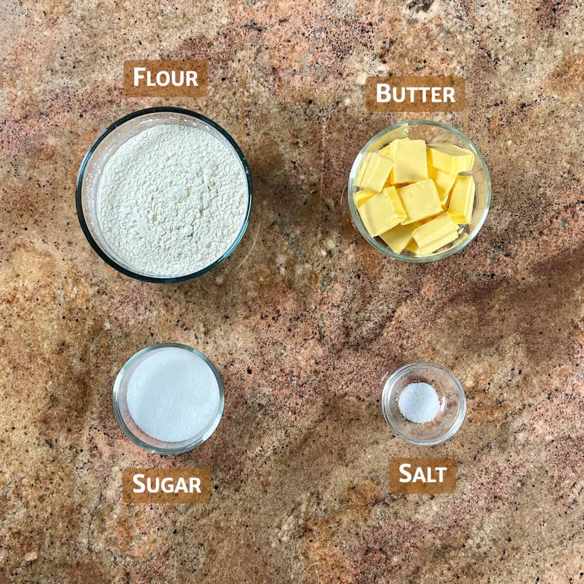 Ingredients for shortbread cutout cookies portioned into glass bowls.