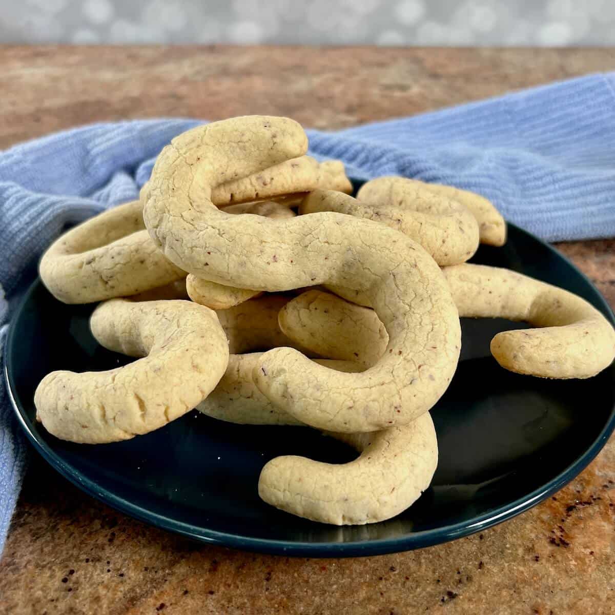A plate of Almond Shortbread cookies that are shaped like an "S" on a blue plate.