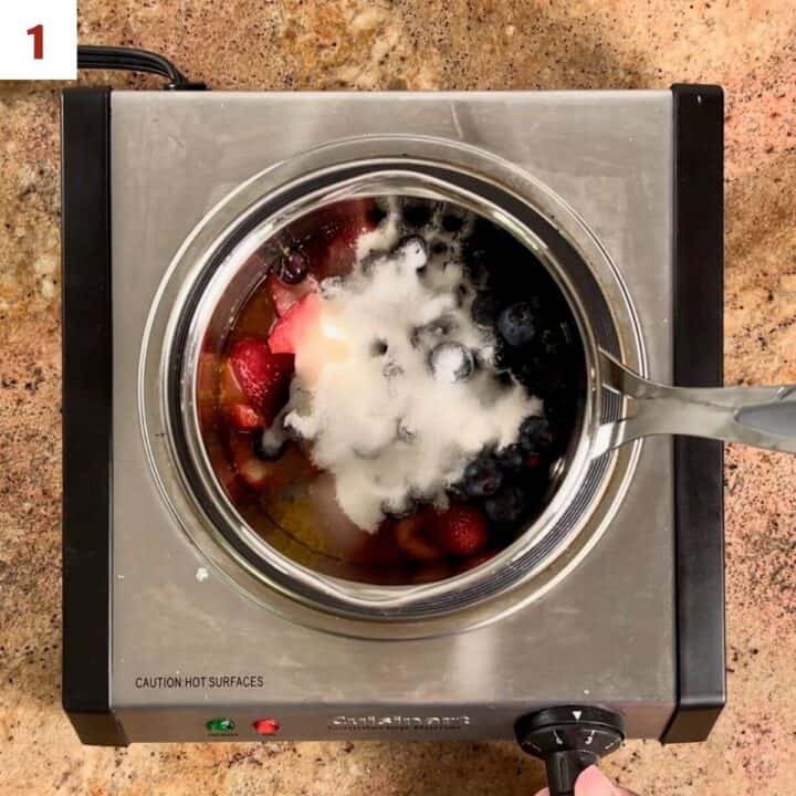 strawberries, blueberries, sugar, and lemon juice in a saucepan on a hot plate.