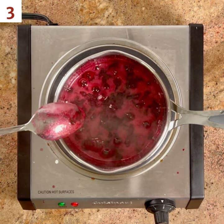 Showing that the jam is ready by seeing if it coats the back of a metal spoon.
