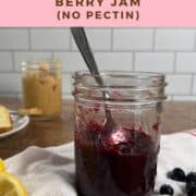 Mixed berry jam in a jar with a spoon inside in front of a jar of peanut butter Pinterest banner.