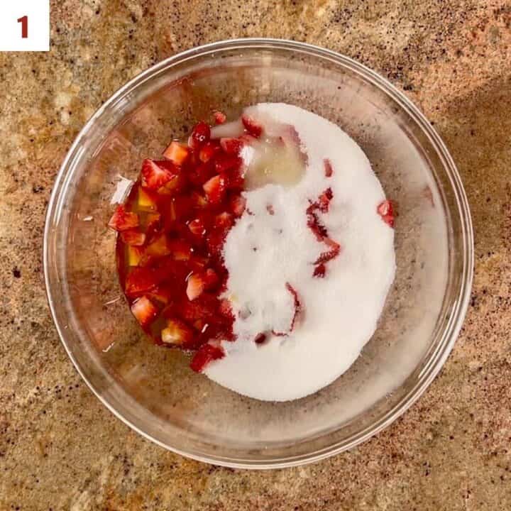 Chopped strawberries, sugar, and lemon juice in a bowl.