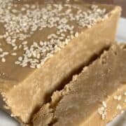 Slice of Tahini Halva next to whole slab on a white plate Pinterest banner.